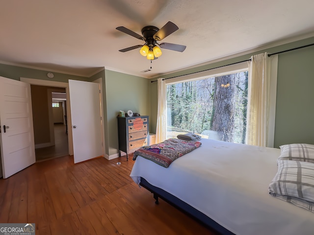 bedroom featuring hardwood / wood-style floors, a ceiling fan, baseboards, visible vents, and crown molding