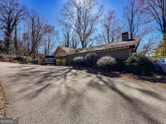 view of side of property featuring driveway and a chimney