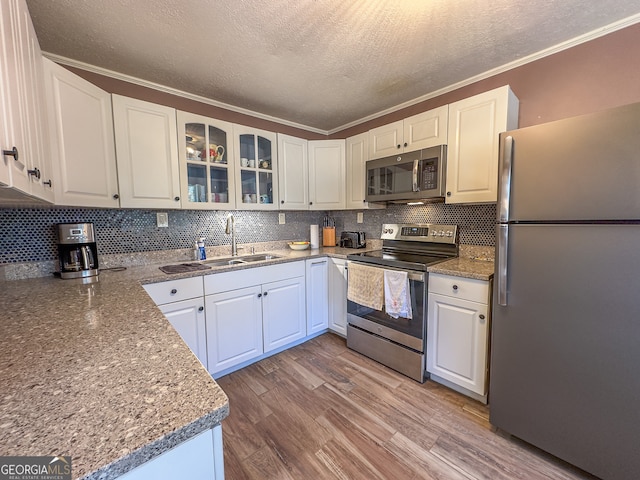 kitchen with light wood-style flooring, a sink, stainless steel appliances, white cabinetry, and tasteful backsplash