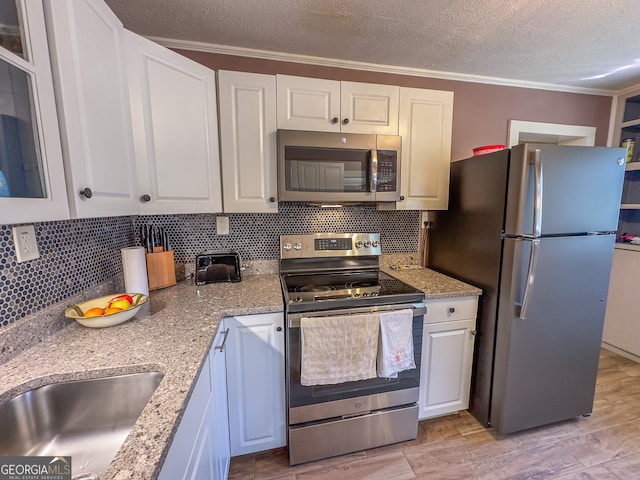 kitchen featuring white cabinetry, decorative backsplash, appliances with stainless steel finishes, and a textured ceiling