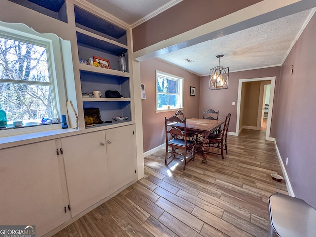 dining space featuring a wealth of natural light, light wood-type flooring, an inviting chandelier, and crown molding