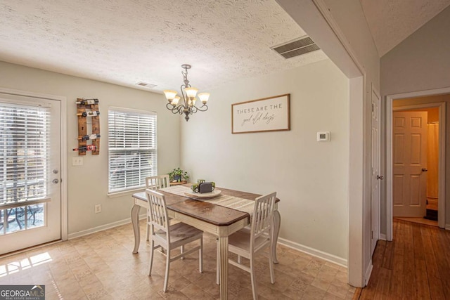 dining room with a chandelier, visible vents, and a textured ceiling