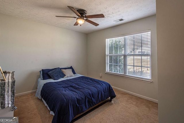 carpeted bedroom featuring visible vents, a textured ceiling, baseboards, and a ceiling fan