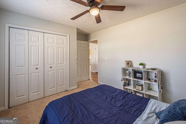 carpeted bedroom with ceiling fan, a closet, and a textured ceiling