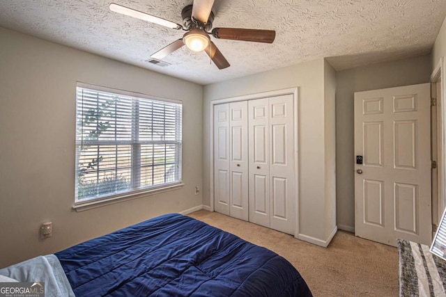 bedroom featuring visible vents, light carpet, a closet, baseboards, and ceiling fan