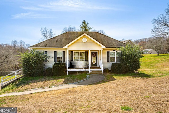 view of front of house with covered porch, a front yard, and fence