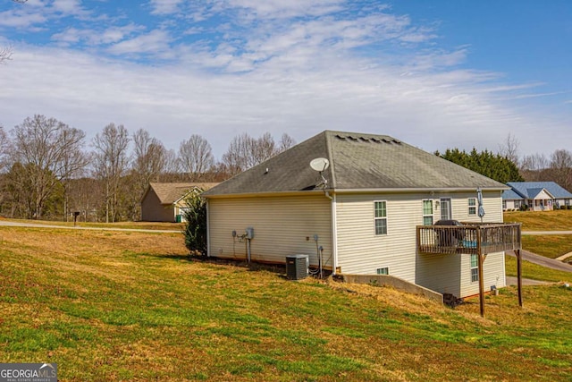 rear view of house with a yard and roof with shingles