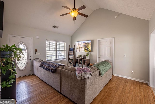 living room with a ceiling fan, baseboards, visible vents, high vaulted ceiling, and wood-type flooring