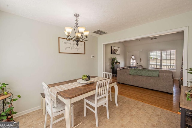 dining space featuring visible vents, baseboards, a textured ceiling, and an inviting chandelier