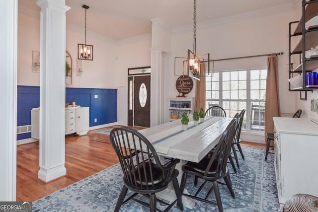 dining room with visible vents, ornamental molding, wood finished floors, an inviting chandelier, and decorative columns