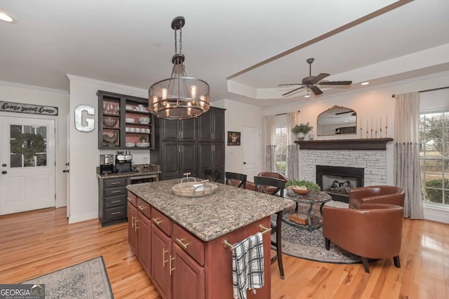 kitchen with a center island, crown molding, light stone countertops, a breakfast bar, and light wood-style floors