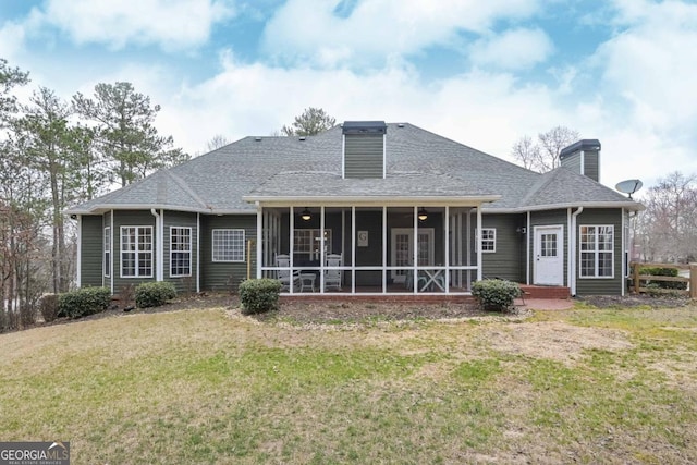 rear view of property featuring a shingled roof, a lawn, a sunroom, and a chimney