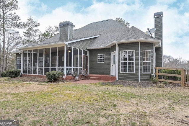 rear view of property featuring fence, entry steps, a lawn, a chimney, and a sunroom