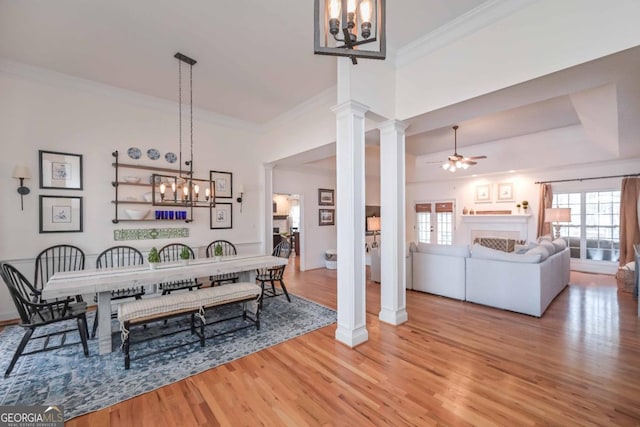 dining room with decorative columns, wood finished floors, crown molding, and ceiling fan with notable chandelier