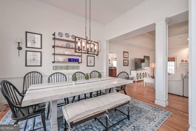 dining space with an inviting chandelier, crown molding, decorative columns, and light wood-type flooring