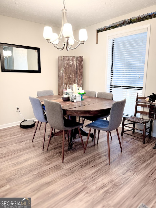 dining space featuring a notable chandelier, light wood-style floors, and baseboards