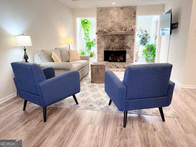 living room with light wood-style flooring, a fireplace, and baseboards