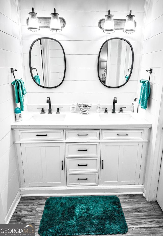 full bath featuring double vanity, wood finished floors, and a sink