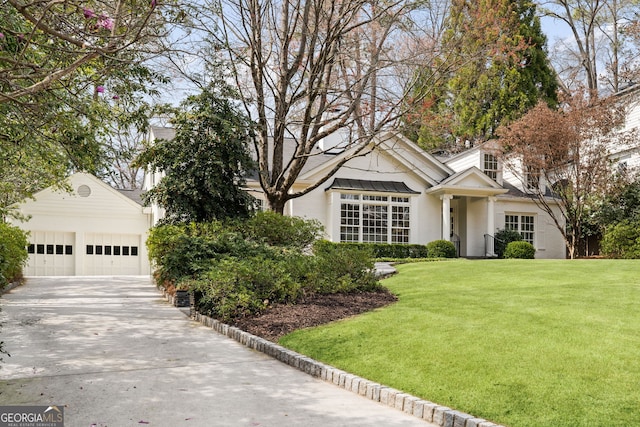 view of front of house with an attached garage, concrete driveway, and a front lawn