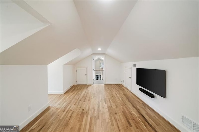 bonus room featuring baseboards, light wood-type flooring, lofted ceiling, and visible vents