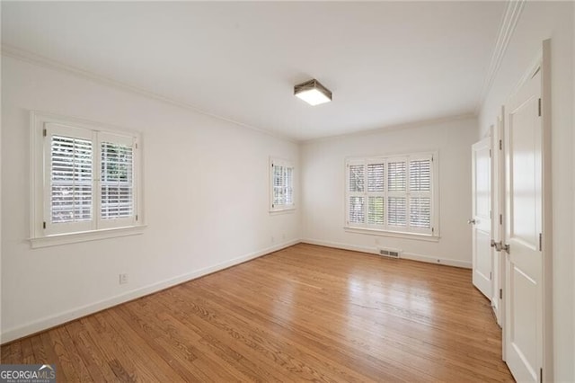 empty room featuring visible vents, baseboards, light wood-type flooring, and ornamental molding