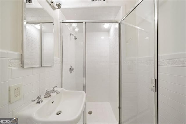 bathroom featuring a sink, tile walls, and a stall shower