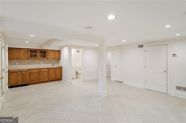 kitchen featuring visible vents, decorative backsplash, brown cabinetry, and light countertops