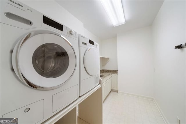 clothes washing area with baseboards, cabinet space, and independent washer and dryer