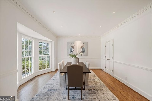 dining room featuring ornamental molding, baseboards, and wood finished floors