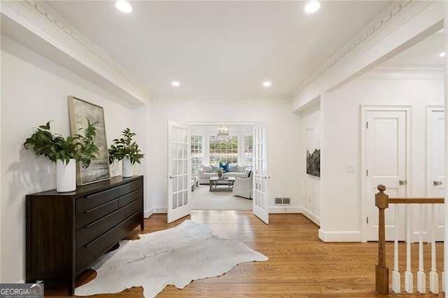 entrance foyer with visible vents, crown molding, baseboards, french doors, and wood finished floors