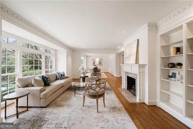 living area featuring baseboards, built in shelves, wood finished floors, and a high end fireplace