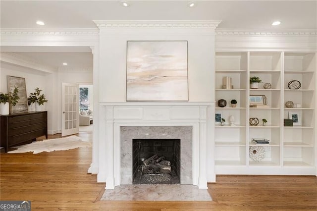 living area with a premium fireplace, recessed lighting, ornamental molding, and wood finished floors