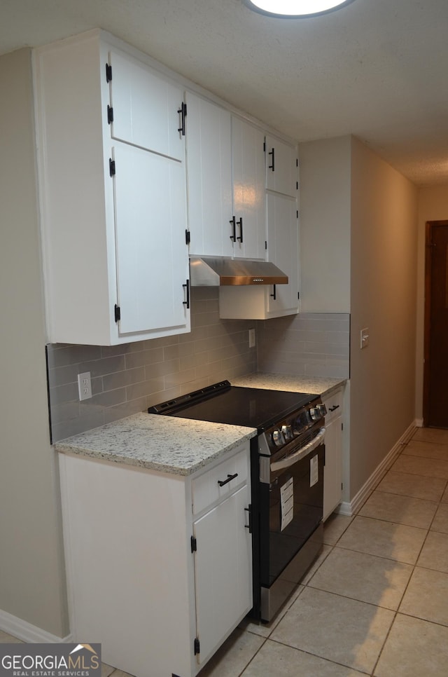 kitchen featuring light tile patterned floors, stainless steel range with electric cooktop, white cabinets, under cabinet range hood, and backsplash