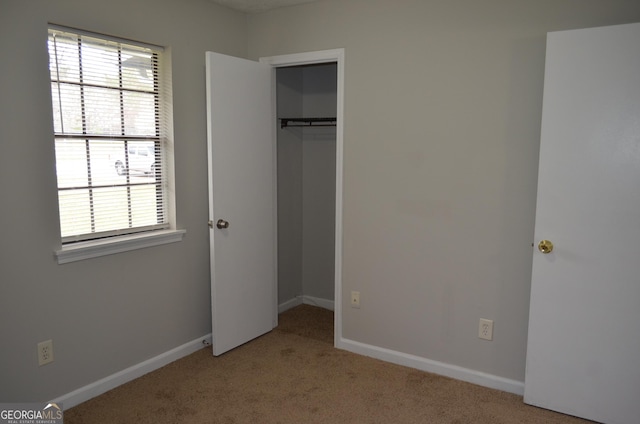 unfurnished bedroom with baseboards, a closet, and light carpet