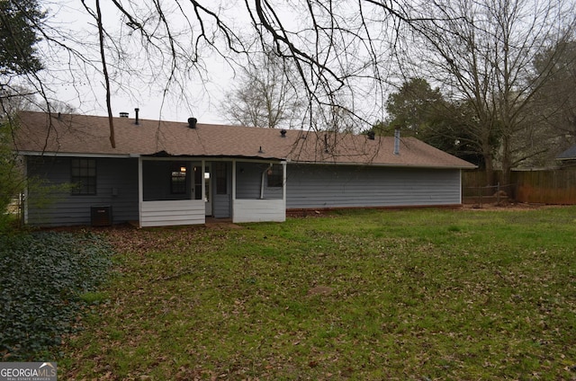 back of house with central air condition unit, roof with shingles, a yard, and fence