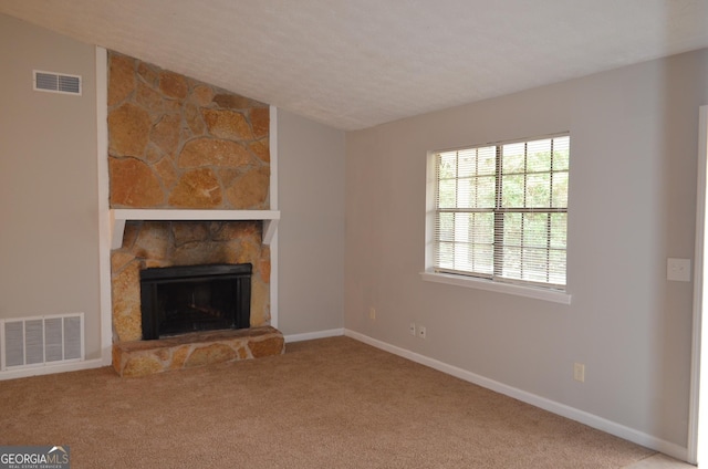 unfurnished living room featuring a fireplace, visible vents, carpet floors, and baseboards