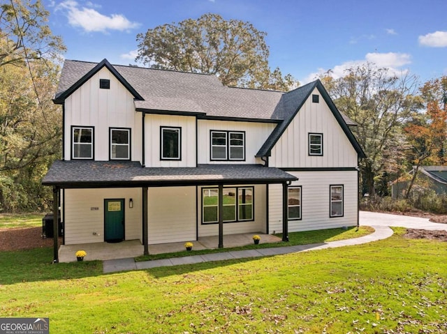 modern farmhouse style home featuring covered porch, board and batten siding, a front yard, and roof with shingles