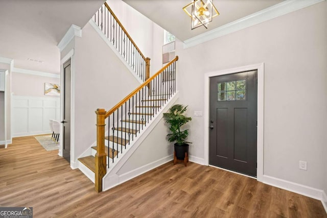 foyer entrance featuring a notable chandelier, stairway, ornamental molding, and wood finished floors