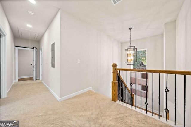 hall featuring attic access, electric panel, carpet flooring, an upstairs landing, and a chandelier