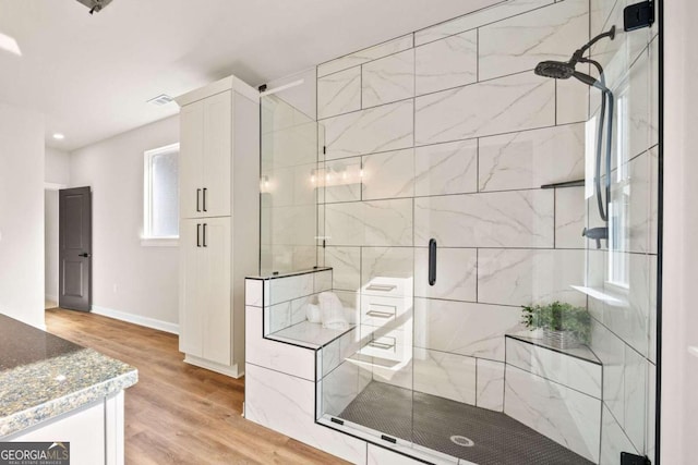 bathroom with vanity, a shower stall, wood finished floors, and baseboards