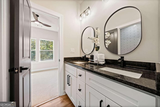 full bath with a sink, baseboards, wood finished floors, and double vanity