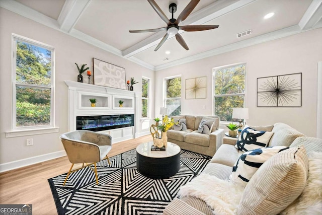 living area featuring a healthy amount of sunlight, wood finished floors, visible vents, beam ceiling, and ceiling fan