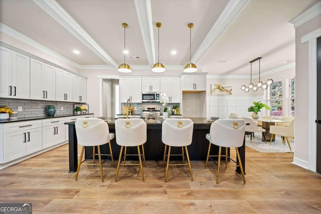 kitchen featuring stainless steel microwave, dark countertops, and light wood-style flooring