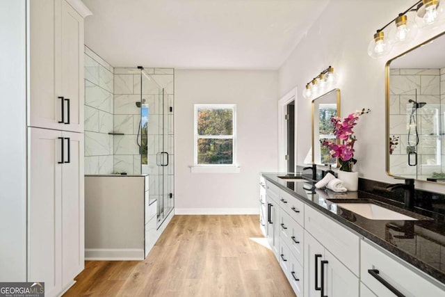 bathroom with a stall shower, wood finished floors, and a sink