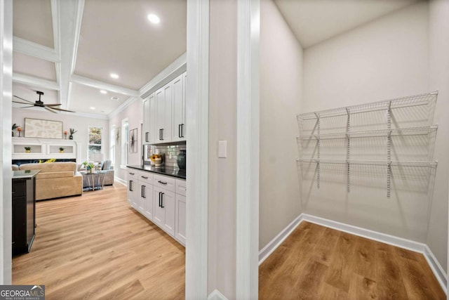 kitchen featuring light wood finished floors, backsplash, white cabinetry, and a ceiling fan