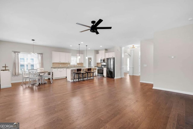 unfurnished living room with recessed lighting, baseboards, ceiling fan, and dark wood finished floors