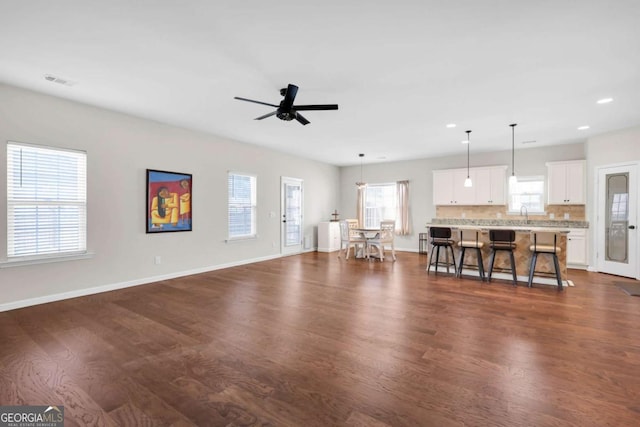 unfurnished living room with visible vents, a ceiling fan, dark wood-style floors, recessed lighting, and baseboards