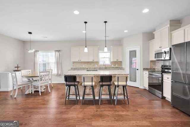 kitchen featuring tasteful backsplash, appliances with stainless steel finishes, a kitchen bar, and dark wood-style flooring