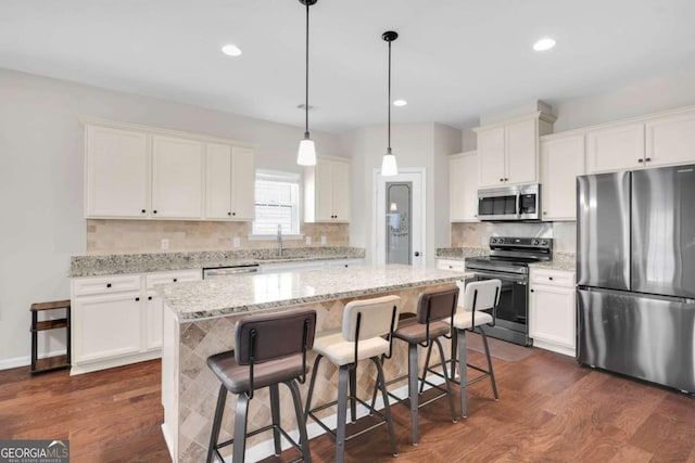 kitchen featuring a sink, stainless steel appliances, a kitchen island, and dark wood-style floors