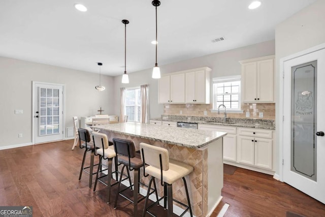 kitchen with a sink, backsplash, dark wood finished floors, and a center island